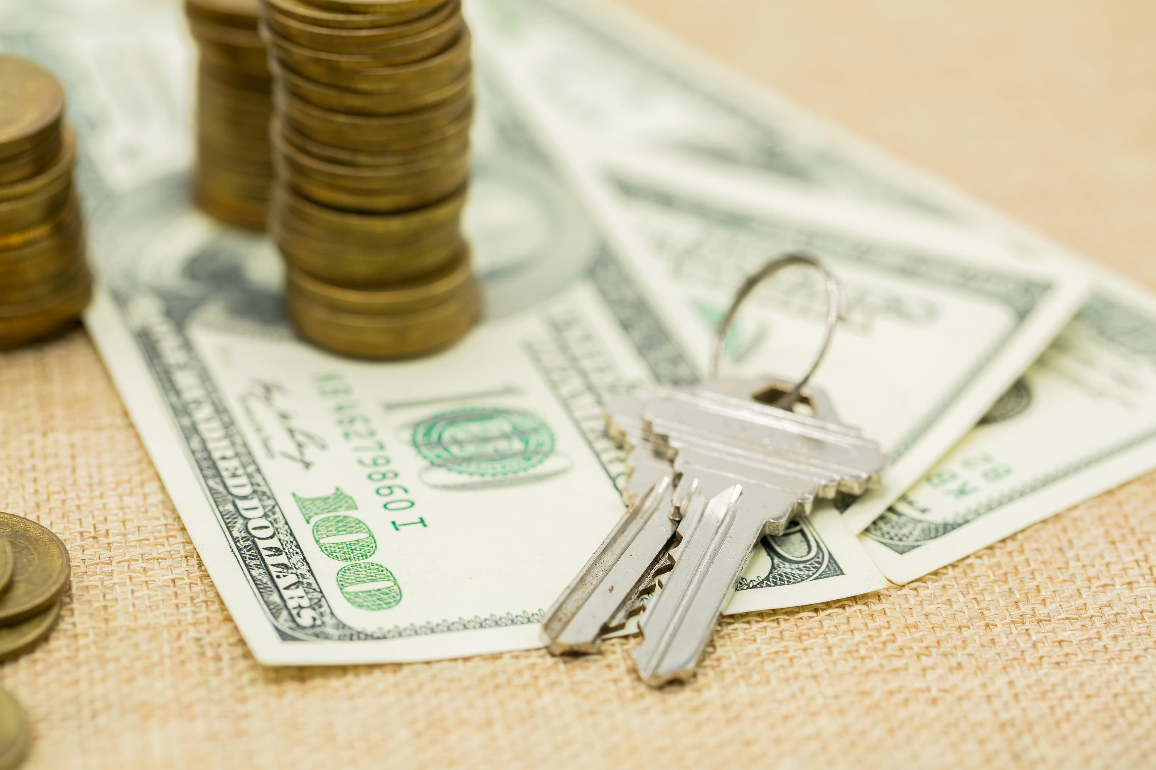 Klucze leżące na banknotach studolarowych i monety